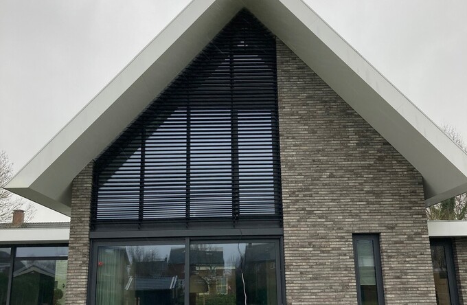 Het vijfhoekig raam van een residentie is voorzien kantelbare lamellen